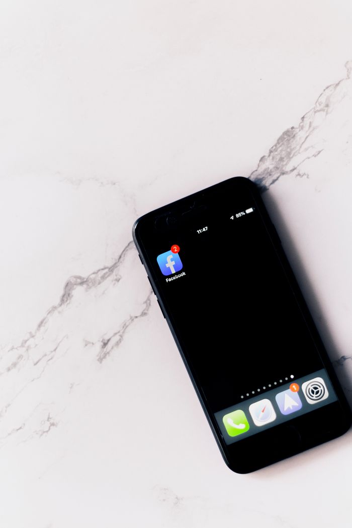 creative-01 Close-up of a smartphone with Facebook app notification on a marble surface.
